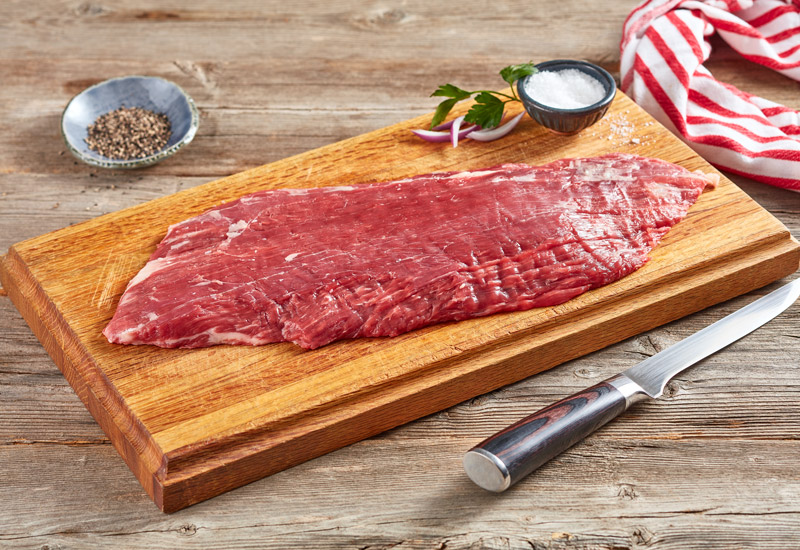 Flank steak on cutting board ready for salt and pepper seasonings